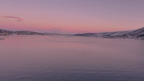 view of the norwegian sea from tromso norway, calm waters and snow covered mountains in the distance