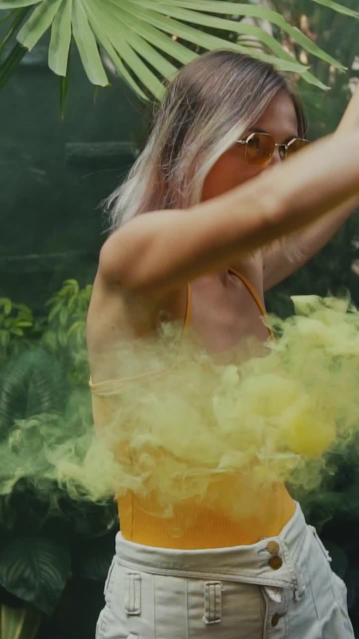 Young relaxed caucasian woman slowly dances using smoke bomb located in nature