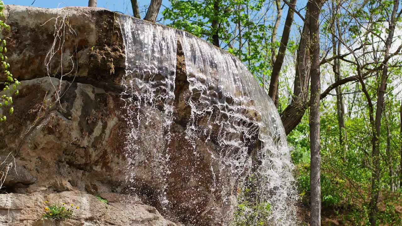 숲 속의 절벽에서 아름다운 폭포: 숲 속에 있는 돌들 사이에서 흐르는 하천, 흐르는 물의 4k 비디오