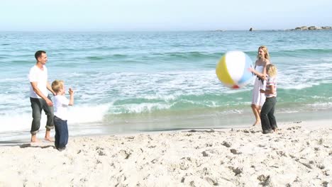 family playing with a ball on the beach