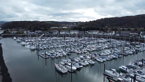 Scenic-luxurious-waterfront-harbour-apartment-village-yachts-and-sailboats-under-mountain-coastline-aerial-view-low-orbit-right