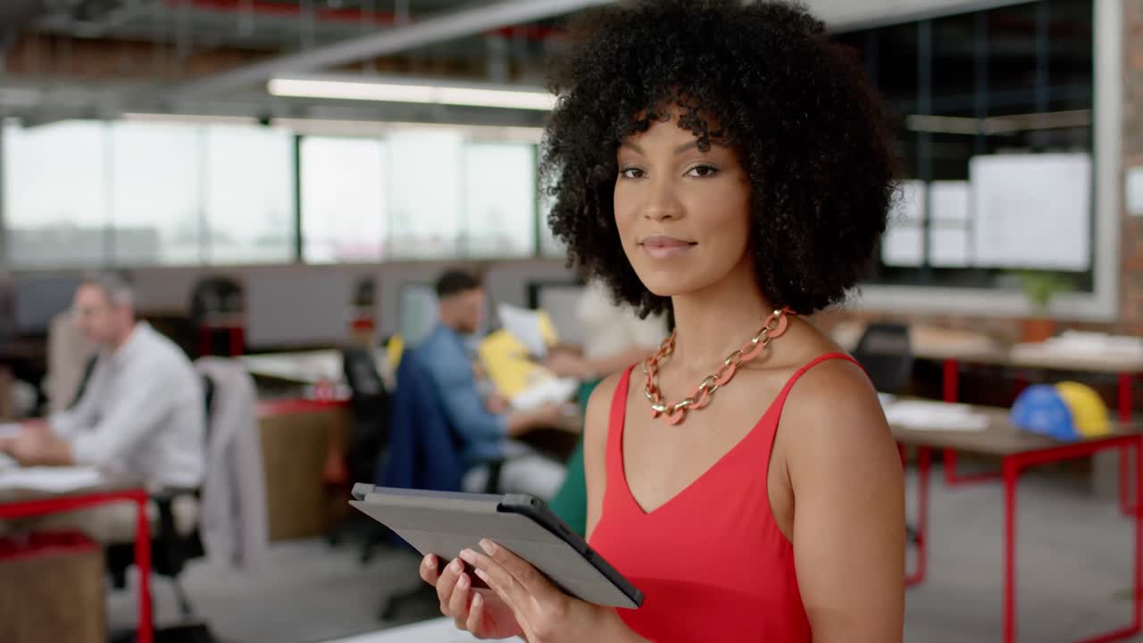 Retrato de uma mulher afro-americana segurando um tablet digital e sorrindo no escritório