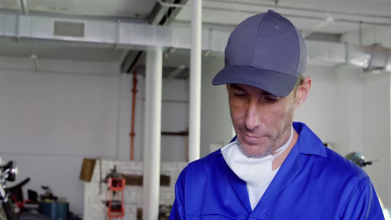 mecánico masculino escribiendo en el clipboard en un garaje de reparación de motocicletas 4k