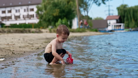 child playing with a toy boat on the beach