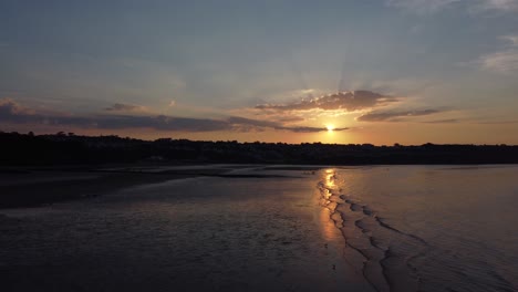 Sonnenstrahlen-Strahlen-Feurig-Goldene-Farben-über-Entspannende-Strand-Ozean-Küste-Luftbild-Dolly-Links-über-Wasser