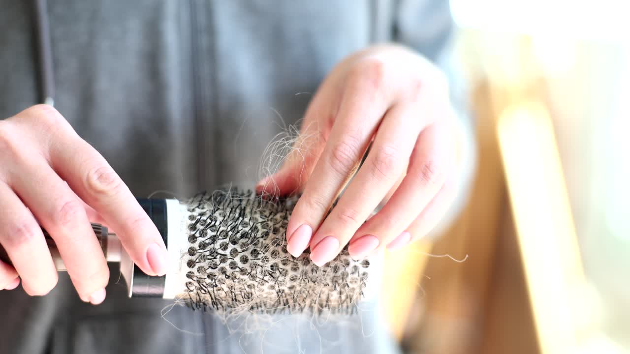 Hair loss on hairbrush held by woman