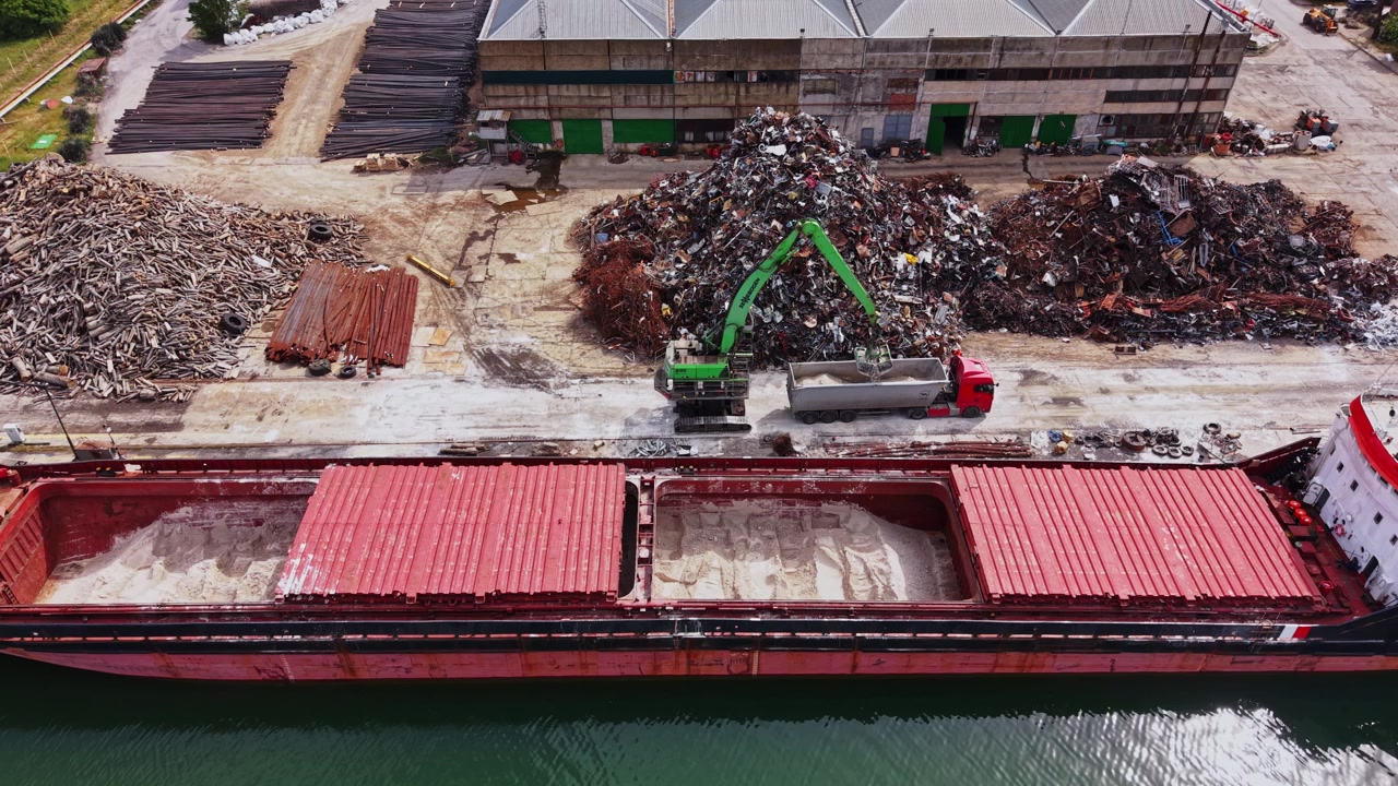 Una grande nave portacontainer si trova in un cantiere di demolizione vicino all'acqua.