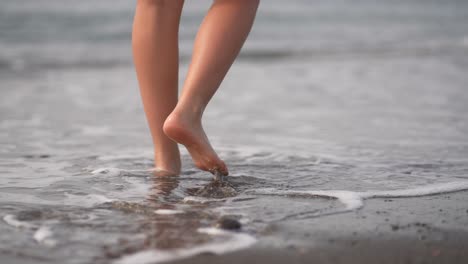 chica caminando sobre una playa volcánica negra con pequeñas olas en fuerteventura, islas canarias