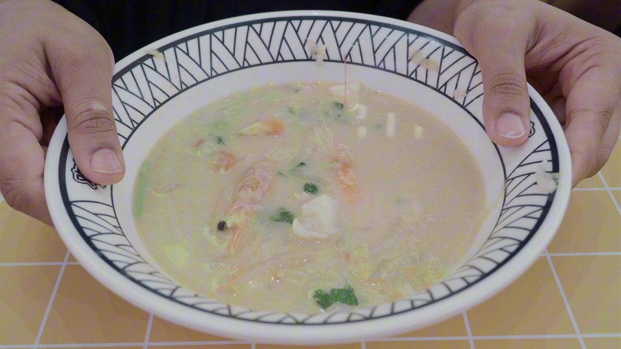 Persona che tiene una ciotola di zuppa cremosa di frutti di mare