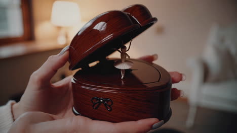 close-up of hands holding a heart-shaped music box with a ballerina