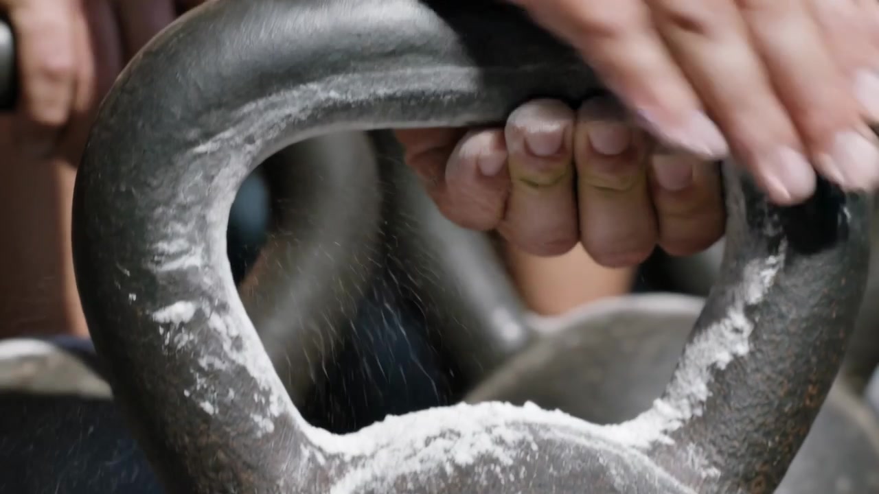 Volwassen handen wrijven magnesium in het gietijzeren handvat van een kettlebell in de sportschool, ter voorbereiding op een lift.