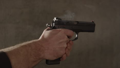 mano masculina disparando una pistola de 9 mm