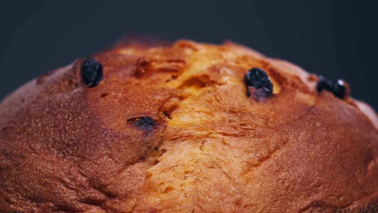 Traditional English Christmas cake tied with a jute thread on the black background. Italian classic Panettone .Pastry Chef sprinkles powdered sugar through a sieve on the fruit Easter cake with raisins. High quality 4k footage
