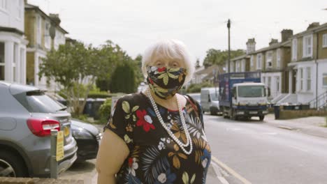 elderly woman wearing a face mask with matching dress looking at the camera smiling