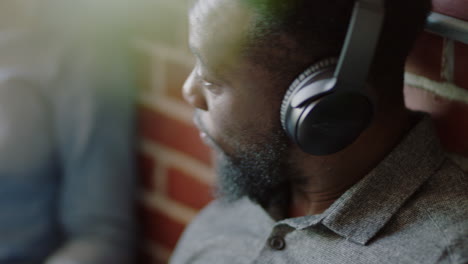 close up happy black businessman chatting to friend listening to music wearing headphones enjoying social communication brainstorming student sharing study ideas relaxing in office workplace