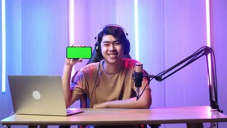 asian man holding mobile phone with mock up green screen while live stream