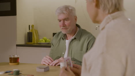 senior man and woman playing poker at home