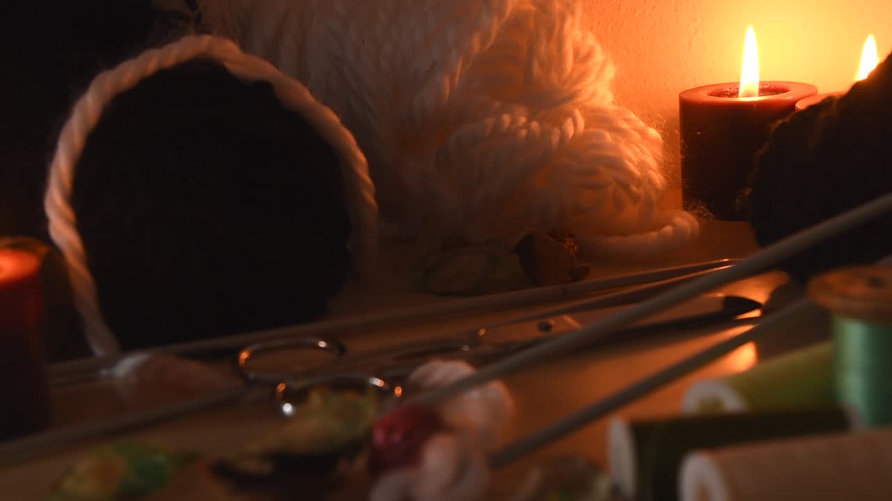 양초와 뜨개질 장비가 있는 뜨개질 테이블의 아늑한 배경