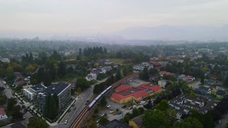 Rail-Train-in-Urban-City-of-Vancouver,-British-Columbia---Aerial-with-Copy-Space