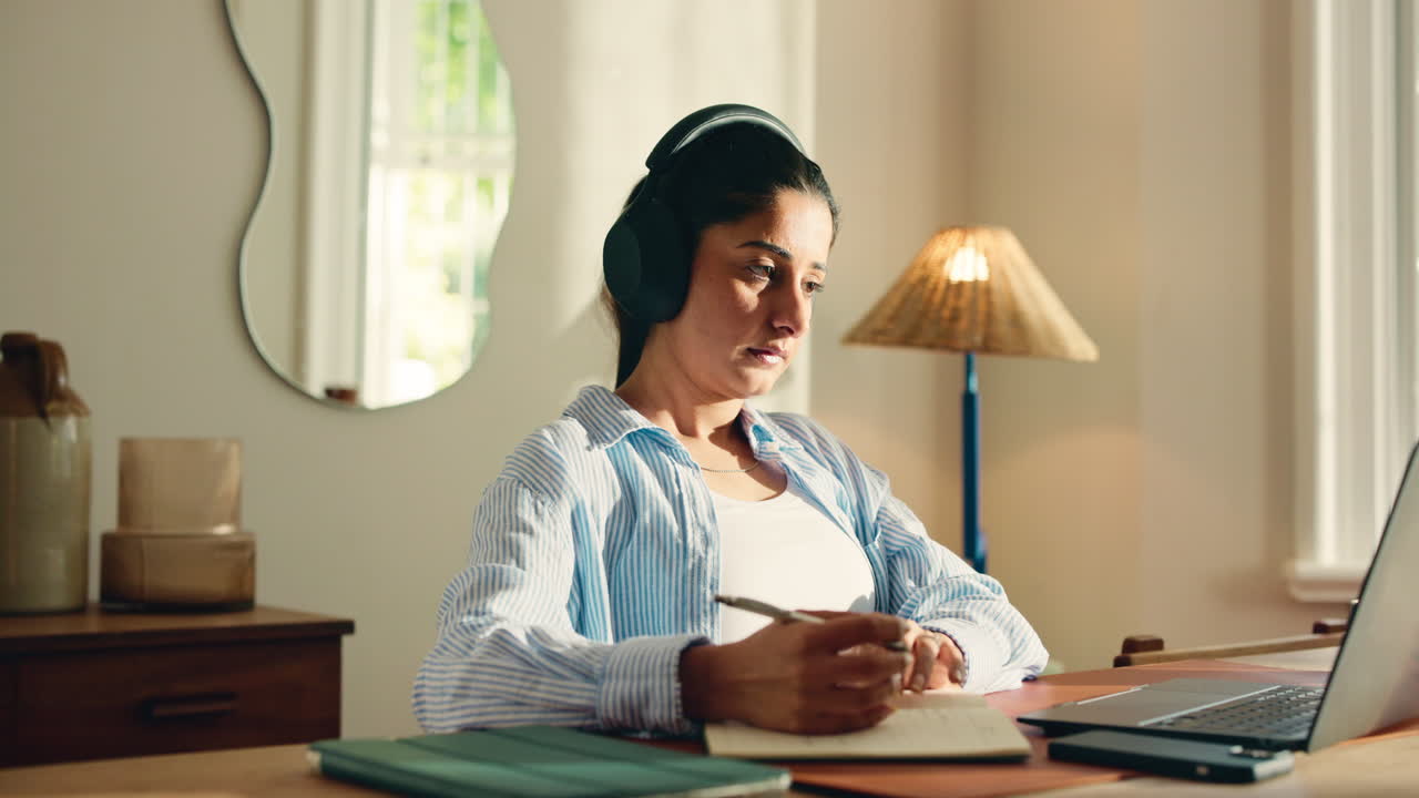Young Woman Puts on Headphones and Writes in Notebook at Home Desk
