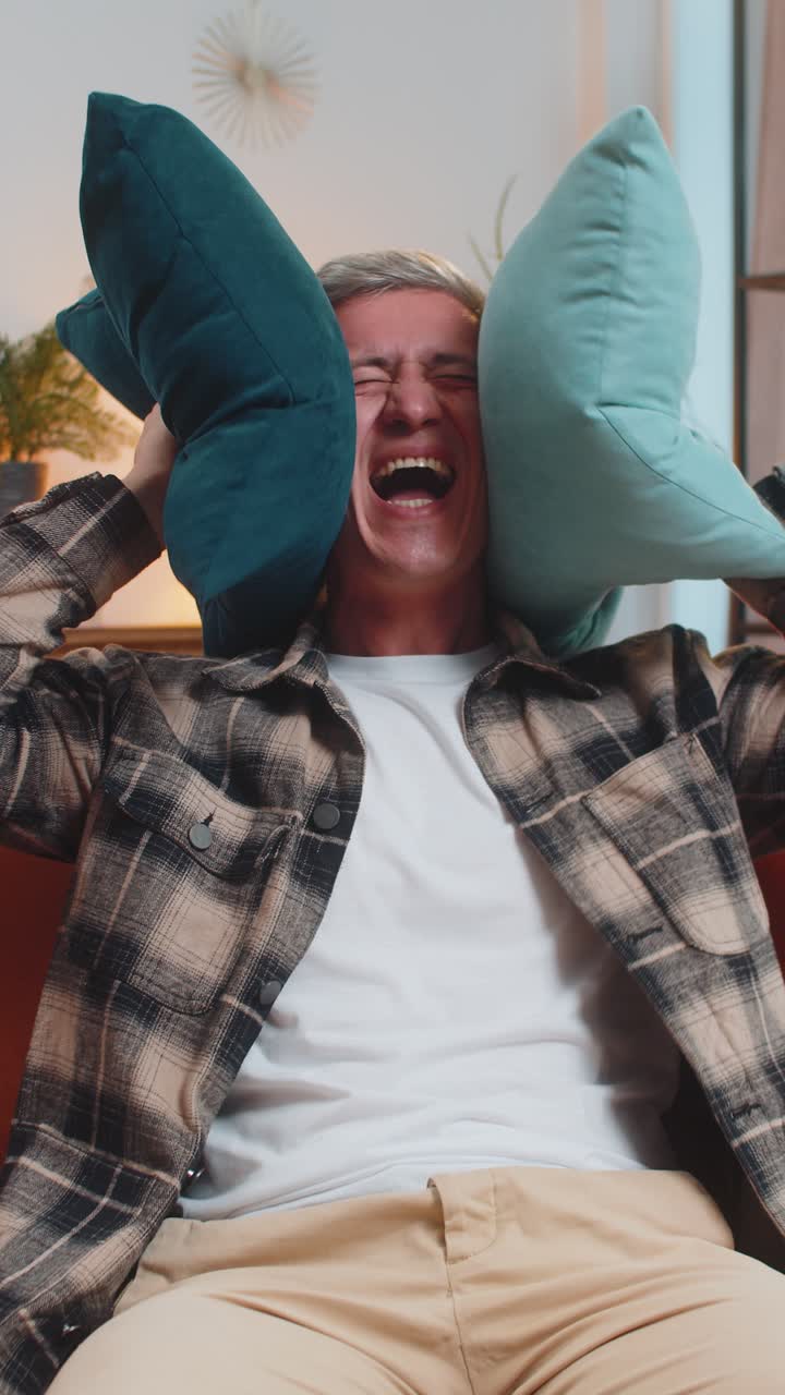 vecinos trabajo de reparación irritado hombre por la música fuerte en casa cubrir las orejas con almohadas molestado por el ruido