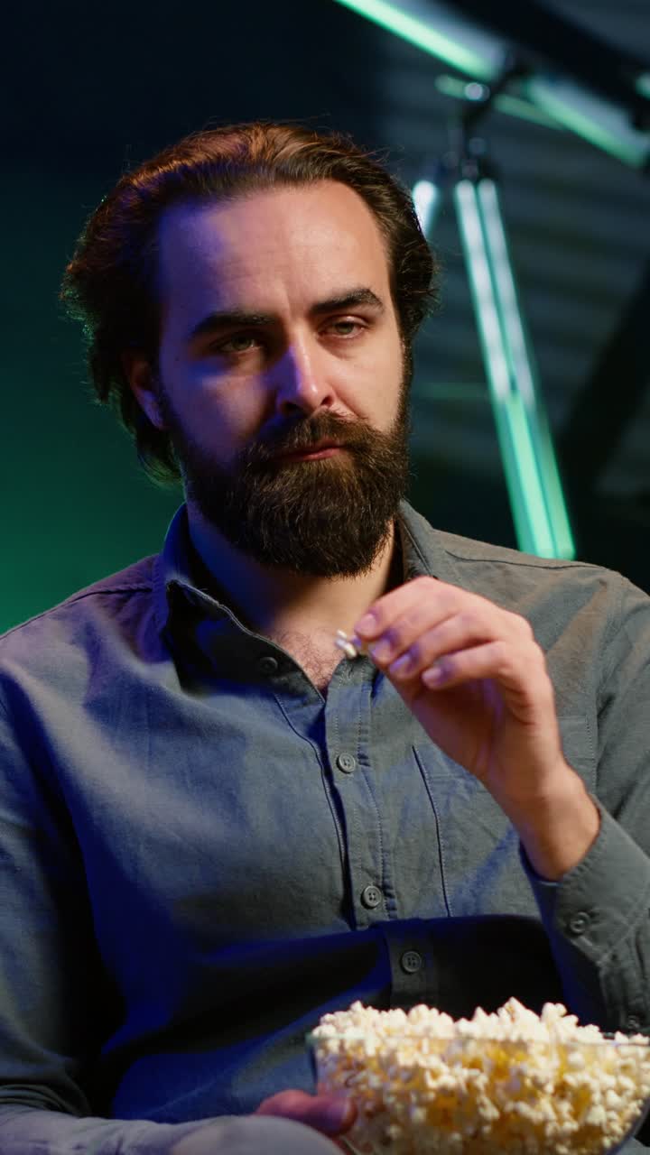 Vertical video Sad man sitting on couch feeling heartbroken while watching tragic movie