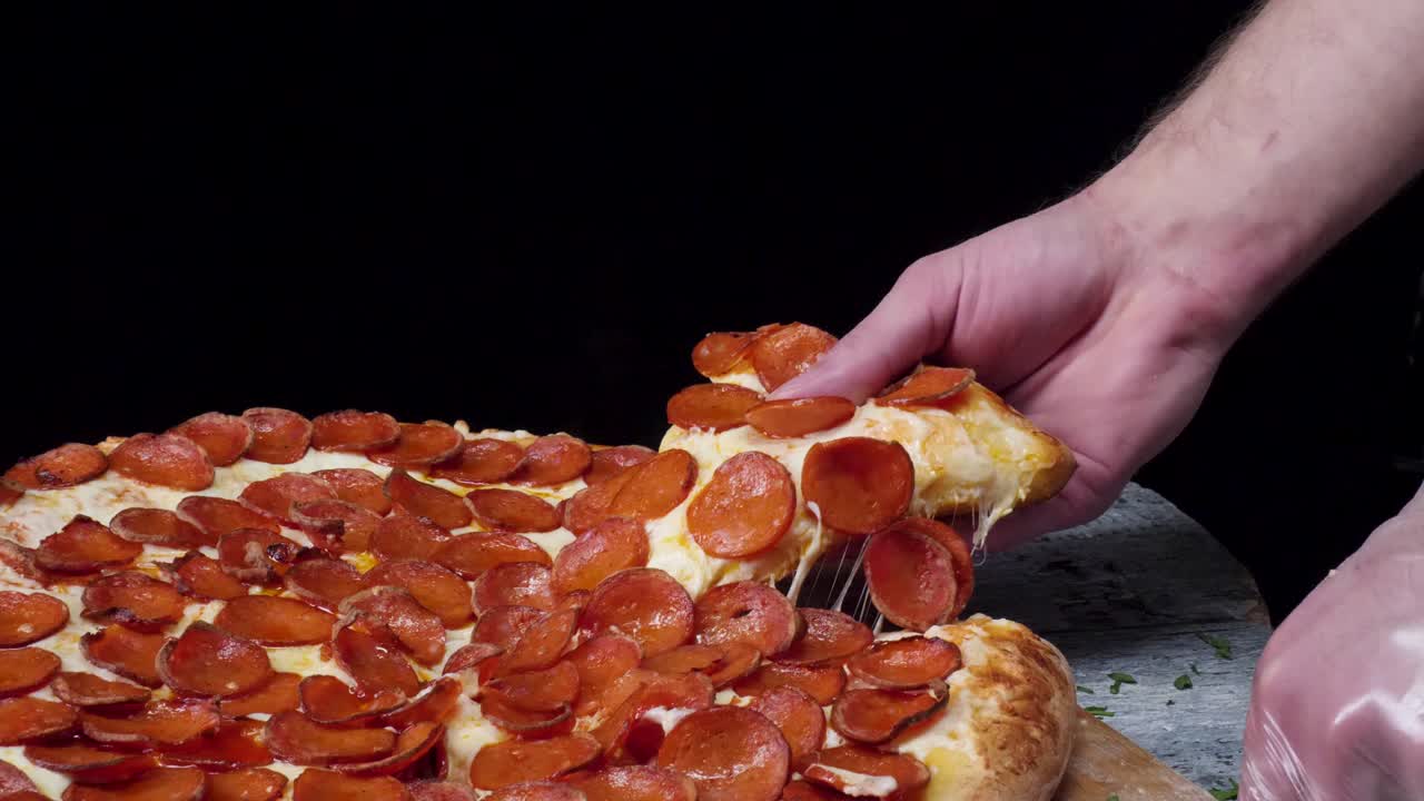 손으로 페페로니 피자 한 조각을 당기고