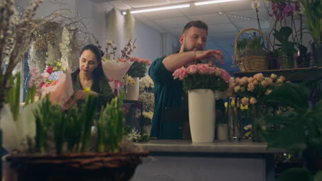 el florista masculino cuenta las flores en el jarrón y toma el pedido usando la tableta