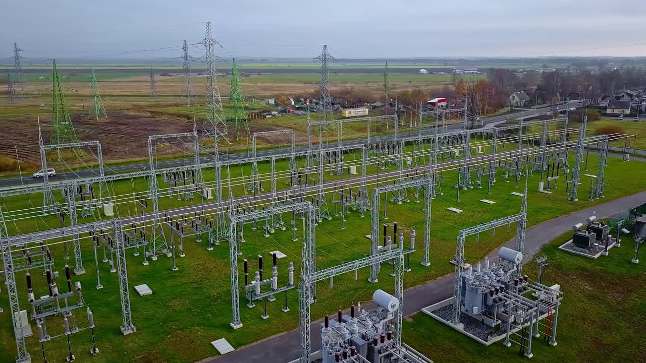 полет беспилотника над электростанцией со всеми отходящими высоковольтными кабелями на высоких столбах
