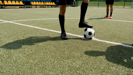 Young-Soccer-Player-Holding-Ball-With-His-Foot-On-Street-Football-Pitch-While-His-Team-Waiting-To-Start-Playing