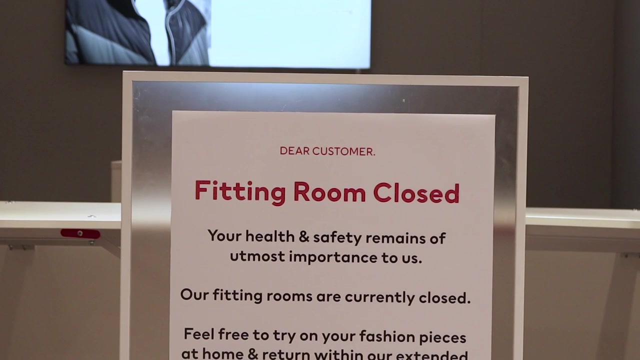 close up on a sign outside a closed fitting room during the national lockdown. covid 19 pandemic corona virus. White sign with red and black text. "Fitting Room Closed"