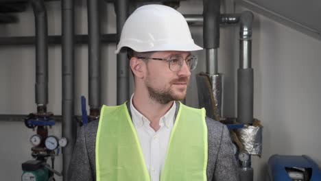 cara de cerca de sonriente arquitecto masculino talentoso con gafas de pie cerca de los sistemas de suministro de agua. ocupado concentrado hombre adulto ingeniero mirando a la cámara positiva. ingeniería profesional.