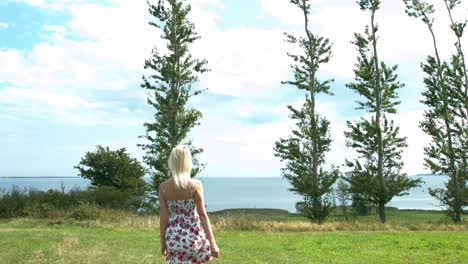 A-woman-walking-alone-in-the-grass-toward-the-water-to-have-a-better-look