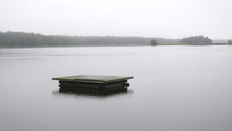 unhappy depression concept, rain falling on isolated swimming platform in dull gray weather, cottage country landscape
