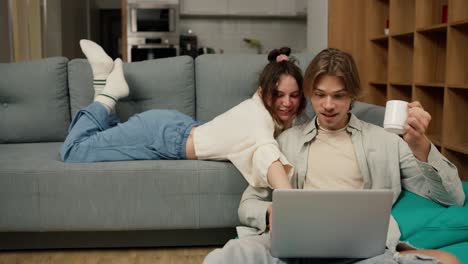 pareja de adultos jóvenes hablando usando una computadora portátil en casa viendo video