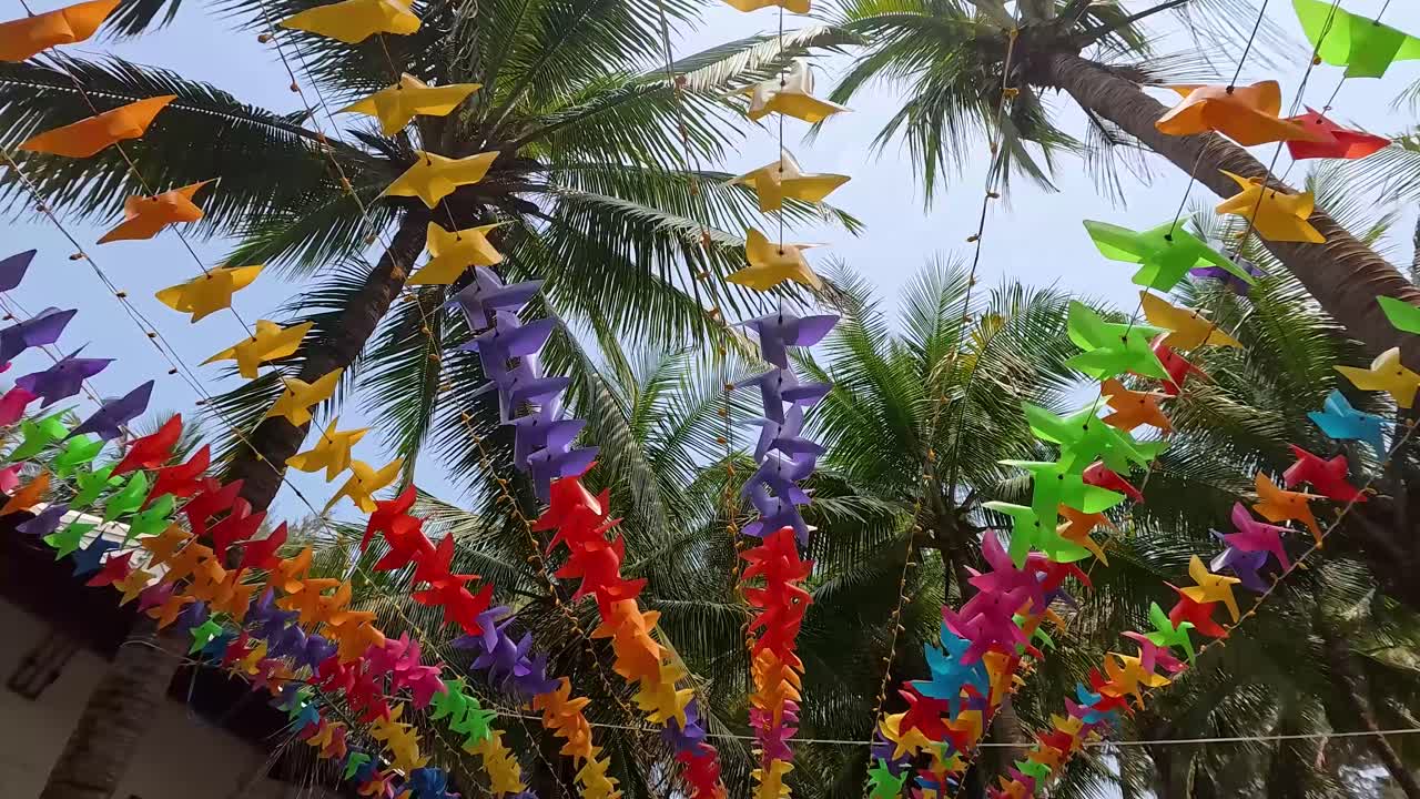 Decorazioni colorate di uccelli di carta tra le palme