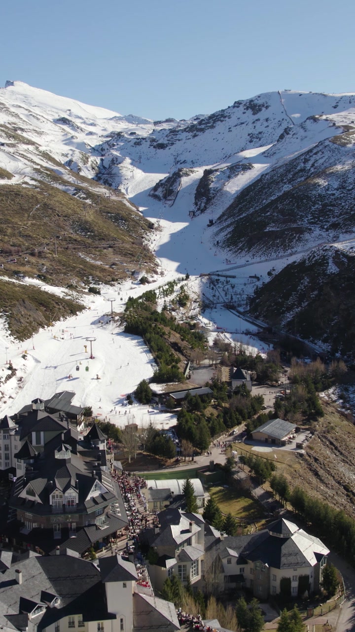 Vertical aerial flying in reverse over ski slopes and a cableway in Spain’s Sierra Nevada mountains.