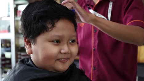 adorable niño asiático feliz peinado en la barbería