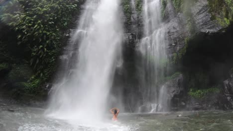 woman standing in strong waterfall, powerful in the jungle