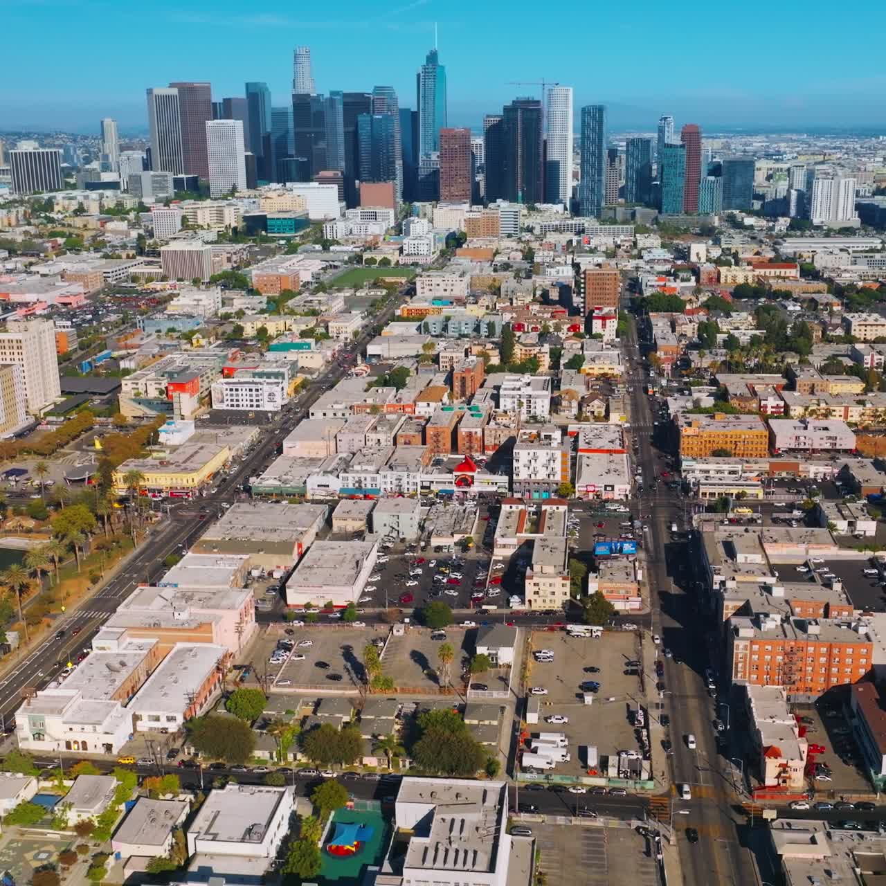 Sunny sight of Los Angeles cityscape. Pond in a park, residential areas and financial downtown with skyscrapers. Aerial view