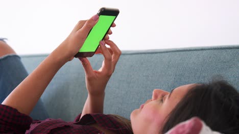 foto cercana de una mujer acostada en el sofá en casa usando un teléfono móvil
