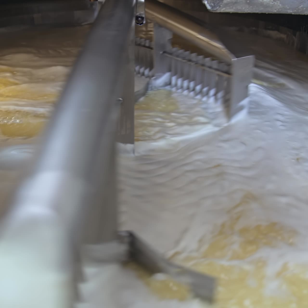 Automatic mixing of fermented milk with two big nozzles in wide tank. Process of cheese production at milk factory. Close up