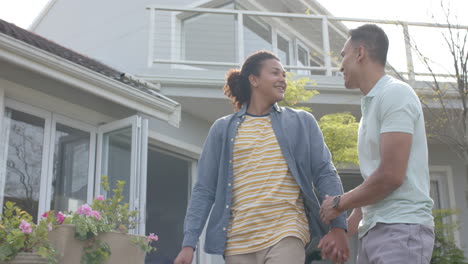 Happy-diverse-gay-male-couple-talking,-walking-in-sunny-garden,-copy-space,-slow-motion