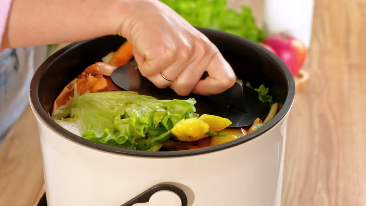 Woman recycling organic waste by composting vegetables peels in the Bokashi in the kitchen