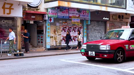 red taxi passing by pedestrians in hong kong