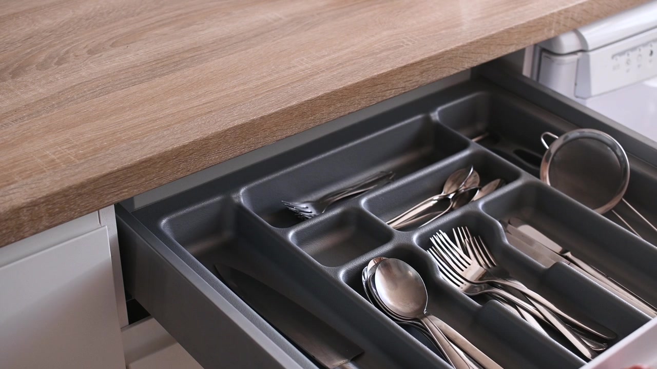 Opening kitchen drawer with organized cutlery and utensils