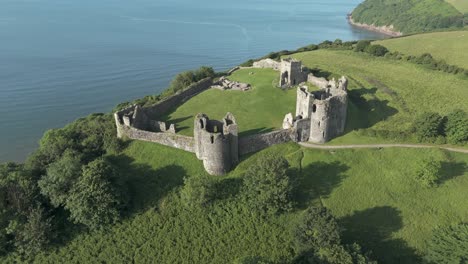 An-aerial-view-of-the-of-Llansteffan-Castle-in-Carmarthenshire,-South-Wales,-on-a-sunny-morning-with-a-clear-blue-sky