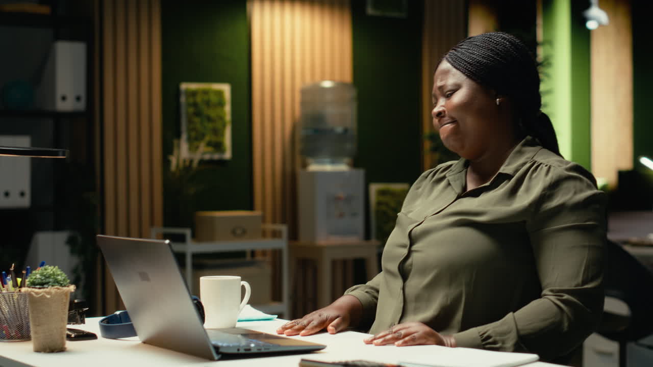 Black businesswoman distressed and burdened at the office after hours