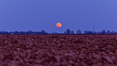 Niedriger-Winkel-Aus-Unfruchtbarem-Boden-Mit-Vollmond,-Der-Sich-über-Eine-Landschaft-Bewegt