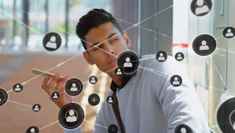 animation of network of connections with icons over biracial businessman talking on smartphone